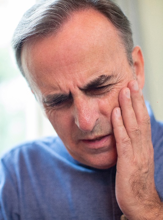 Man holding his cheek in pain