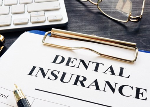 A dental insurance form and pen on a desk