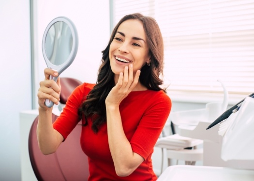 Woman in dental chair admiring her smile in mirror