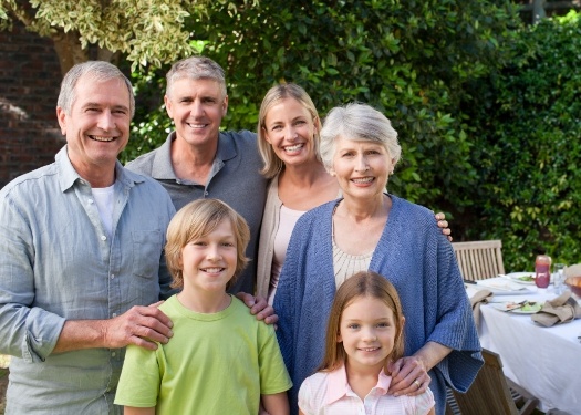 Three generations of family smiling in backyard