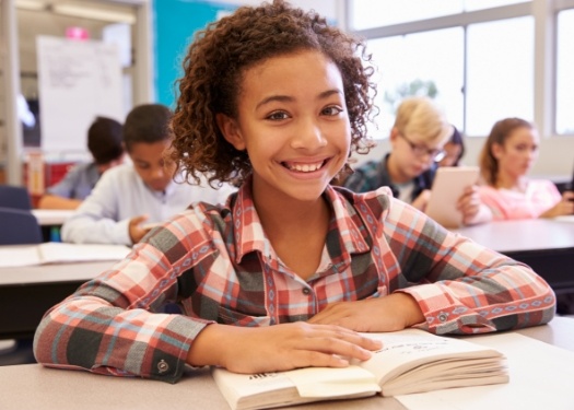 Child smiling while sitting at school desk