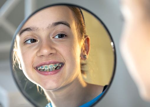 Teen girl looking at her braces in mirror