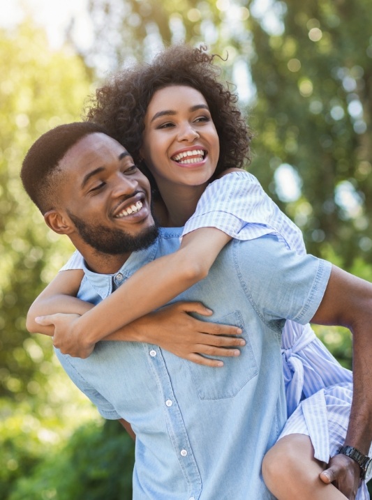 Smiling young man and woman holding each other outdoors