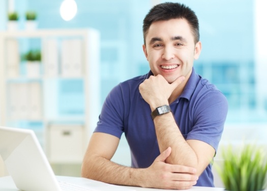 Smiling man sitting at desk with laptop
