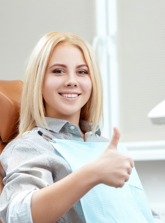 Woman in dental chair giving a thumbs up