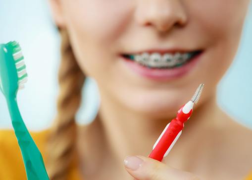 Person with braces holding toothbrush and interdental brush
