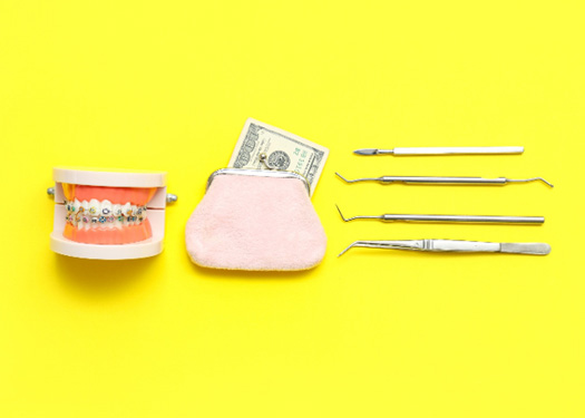 A pair of fake teeth with braces, money, and dental tools