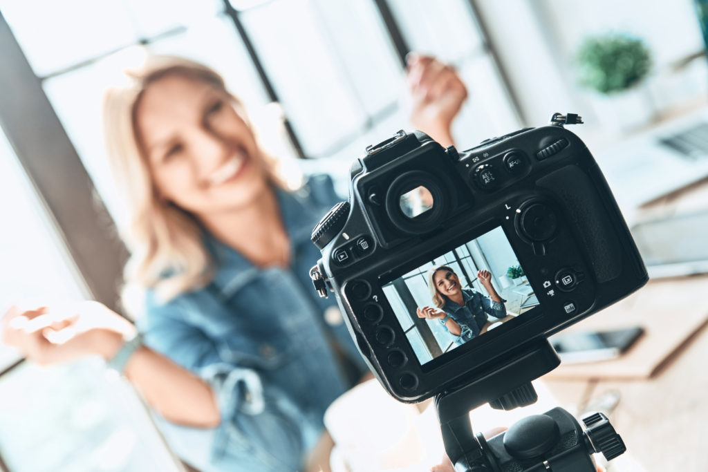 person smiling while being filmed with a camera