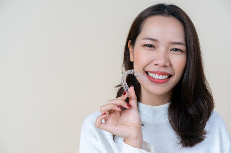 person holding clear aligner and smiling