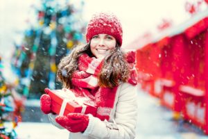 Smiling woman holding a gift in the snow