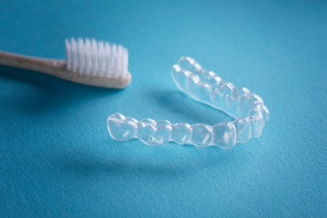 A clear aligner tray sitting next to a toothbrush